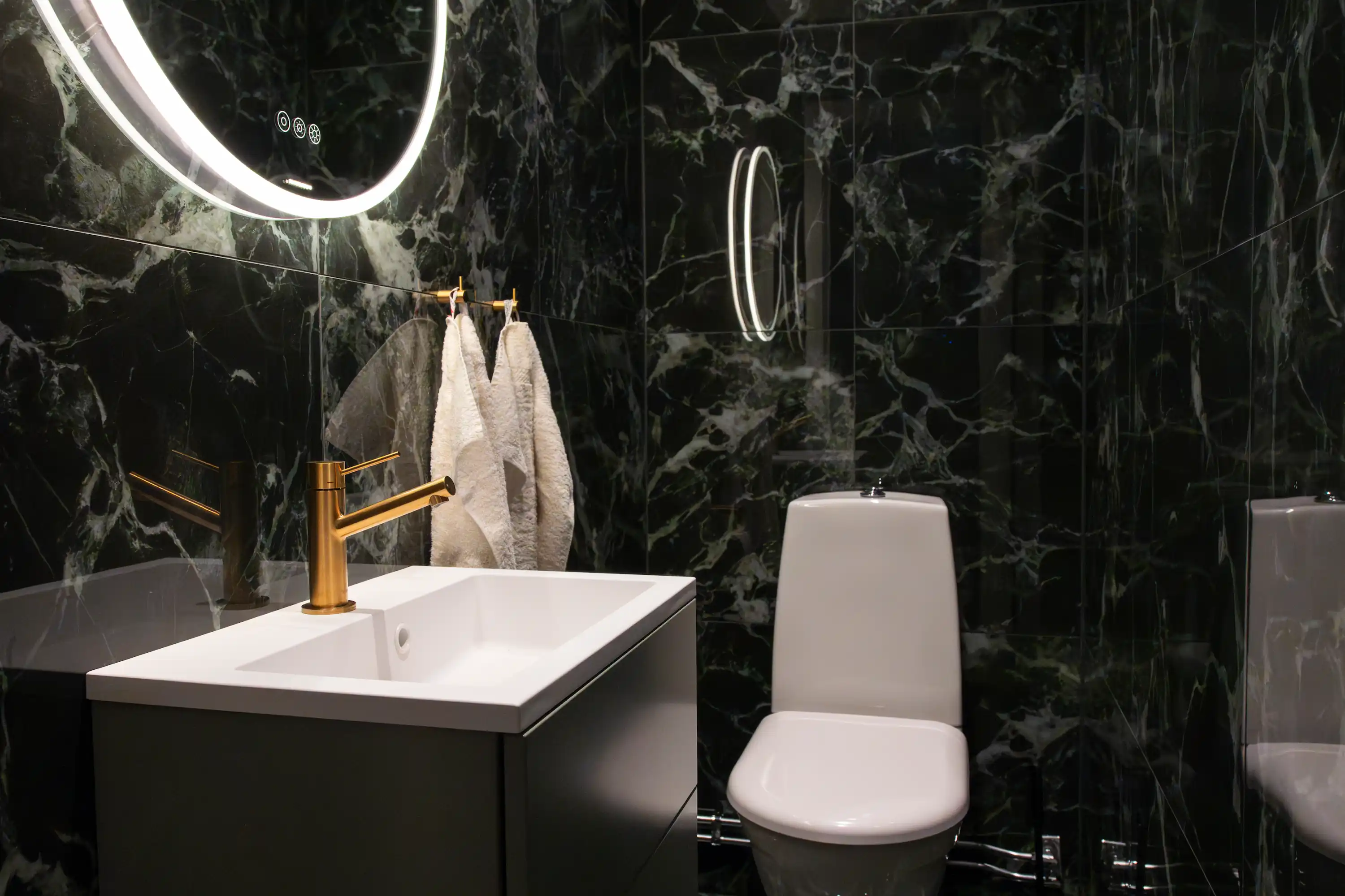 badrumsrenovering efter-bild med wc, grönt kakel, spegel och kran i mässing