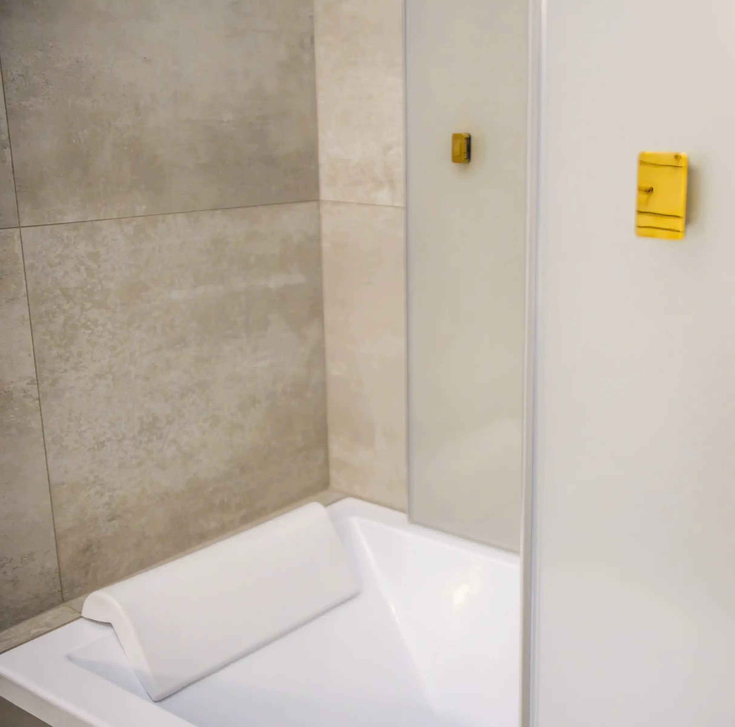 badkar med ljust kakel , nackkudde och immig glasvägg